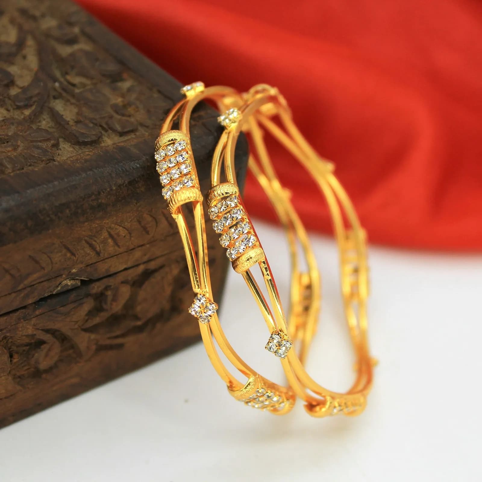Nakshi Rose Gold Bangle - A pair of gold bracelets sitting on top of a wooden box