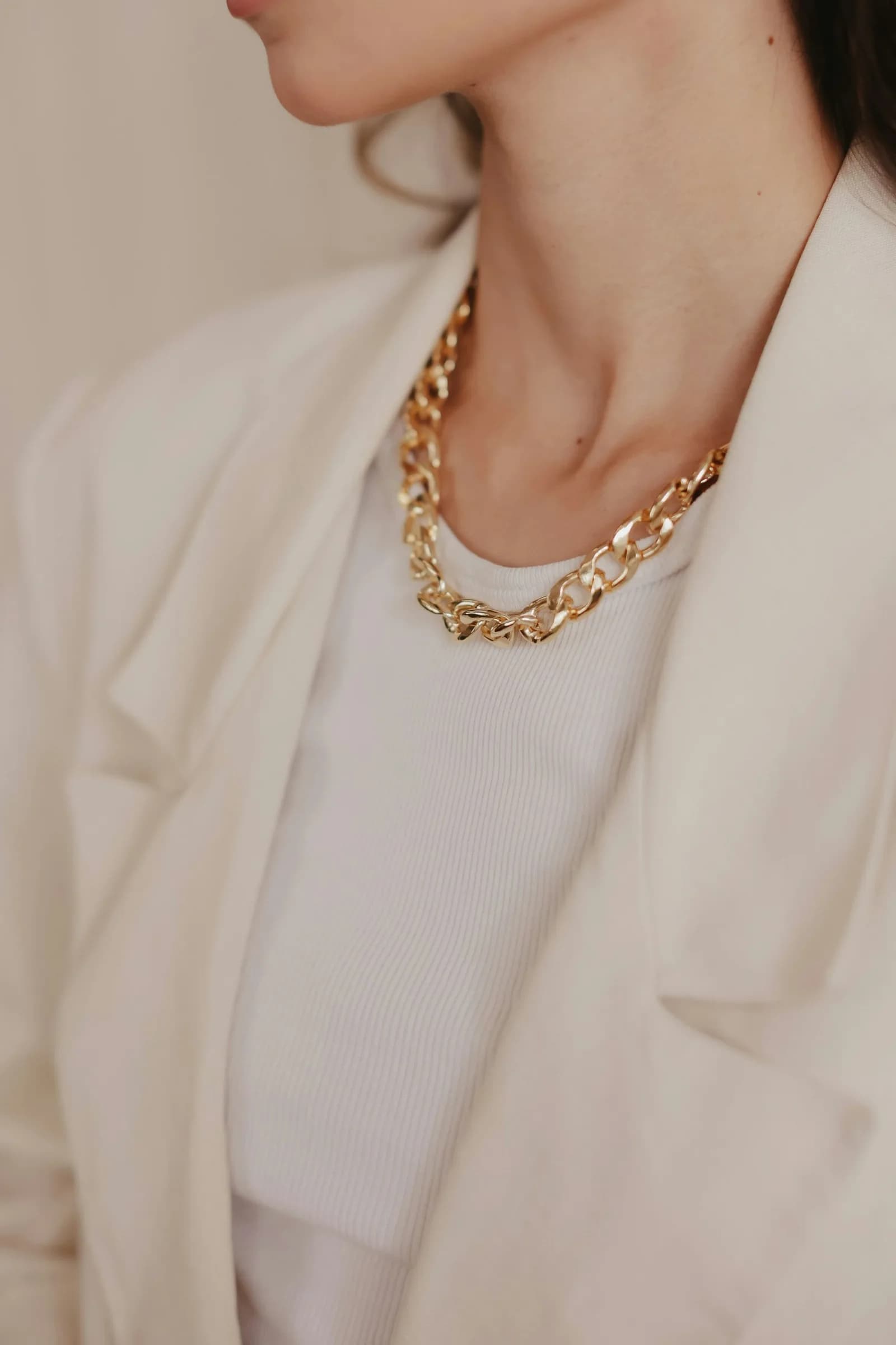 Layered Kundan Mangalsutra - A woman wearing a white jacket and a gold necklace
