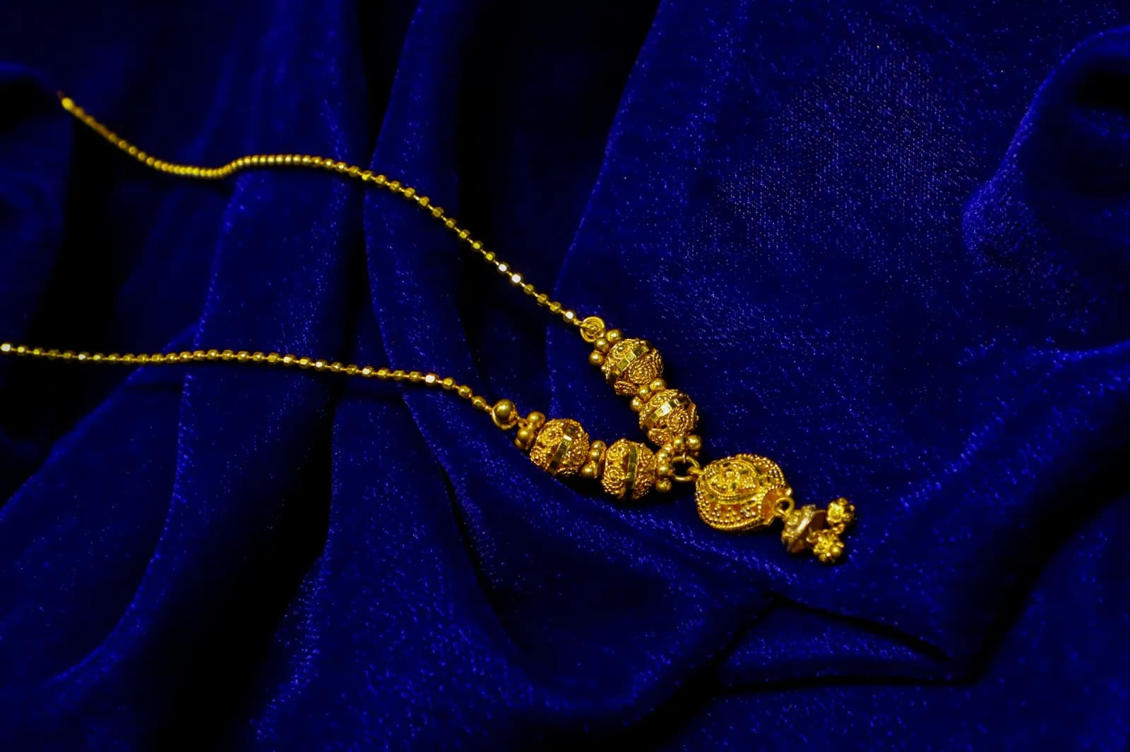 Meenakari Antique Gold Necklace - Gold necklace with intricate bead details on blue velvet